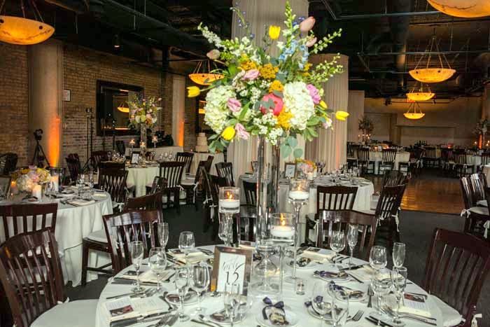 Wedding reception tables with tall floral arrangements and candlelight